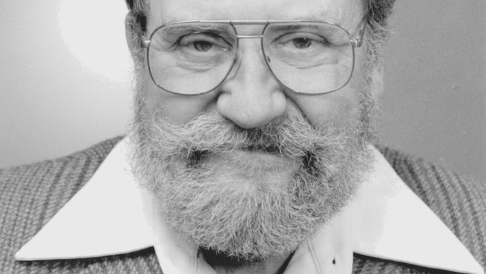 Black and white headshot of Ray Owen wearing a bolo tie