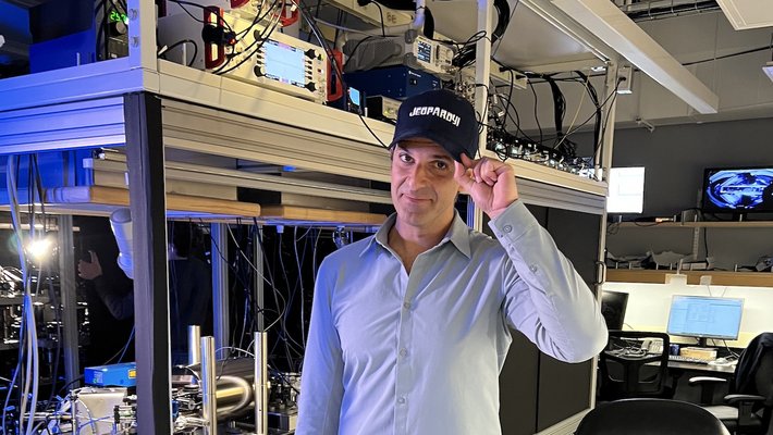 Spiros Michalakis wearing a blue shirt and a baseball hat that reads "Jeopardy!"