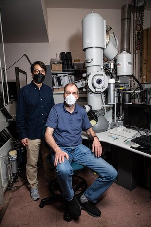 Professor Axel Scherer and graduate student Changsoon Choi posed in a basement lab next to an electron microscope.