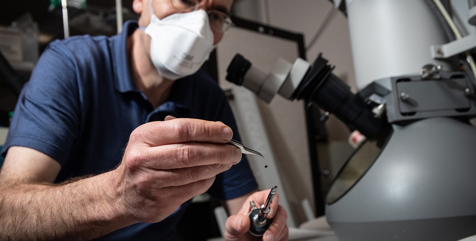 Professor Axel Scherer working at the electron microscope, holding a sample between Tweezers