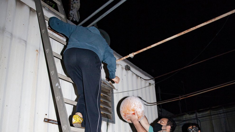 Woman on ladder helps carry pumpkin to roof