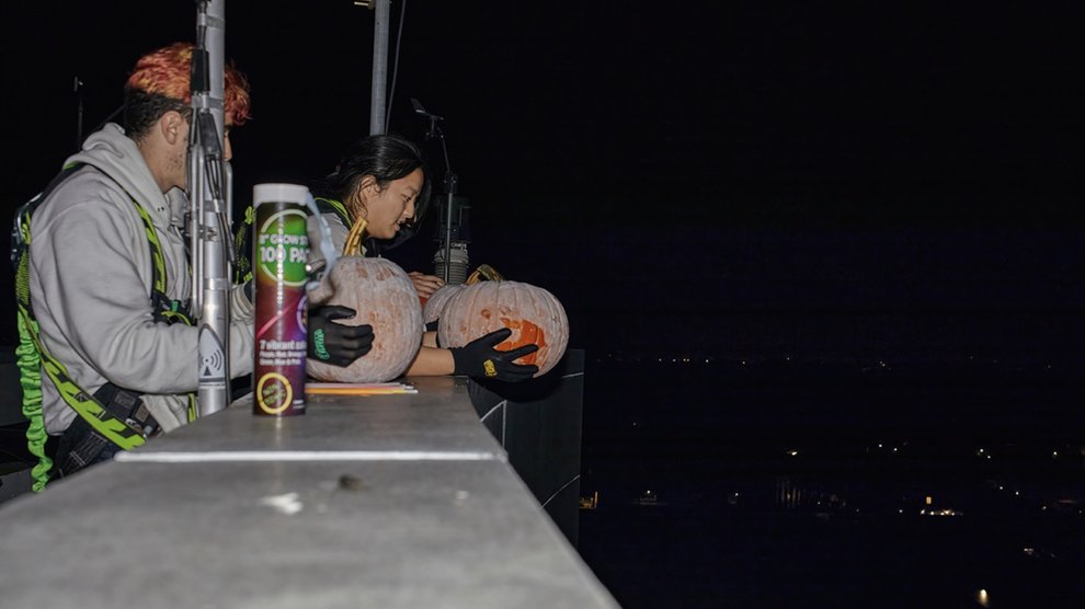 Woman prepares to drop pumpkin from roof