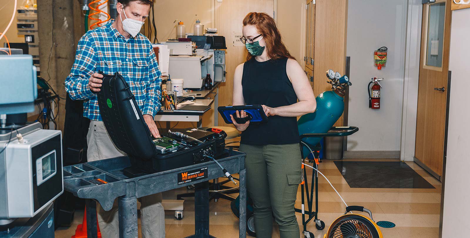 two people wearing masks, looking GasScouter (methane detector)
