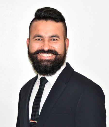 A man in black jacket and tie smiles for a photo