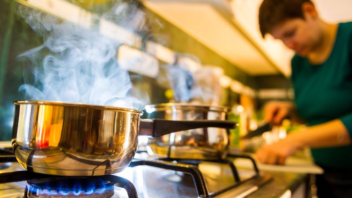 person cooking in front of a gas stove