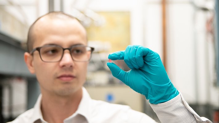 Christopher Simon holds a pink crystal made of lithium holmium yttrium fluoride.
