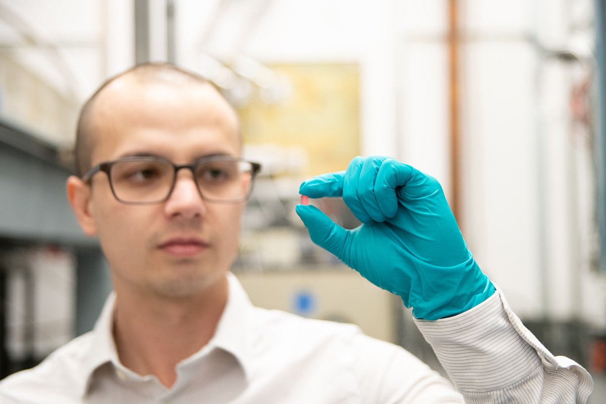 Christopher Simon holds a pink crystal made of lithium holmium yttrium fluoride.