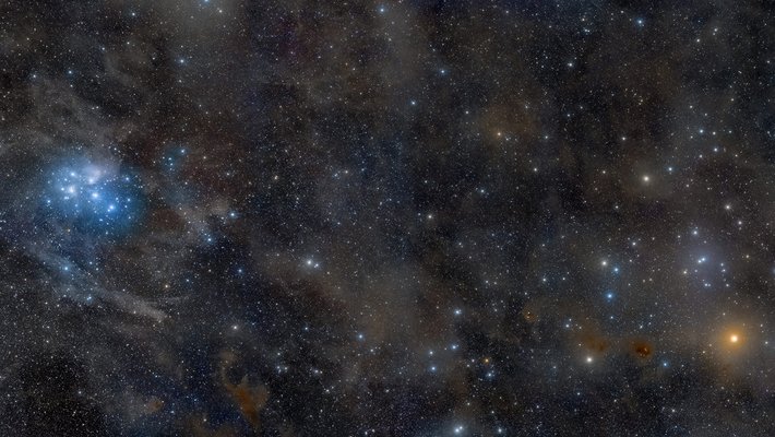 The night sky, showing the Pleiades, a collection of stars on the left center of the image, and the star Aldebaran on the lower right.