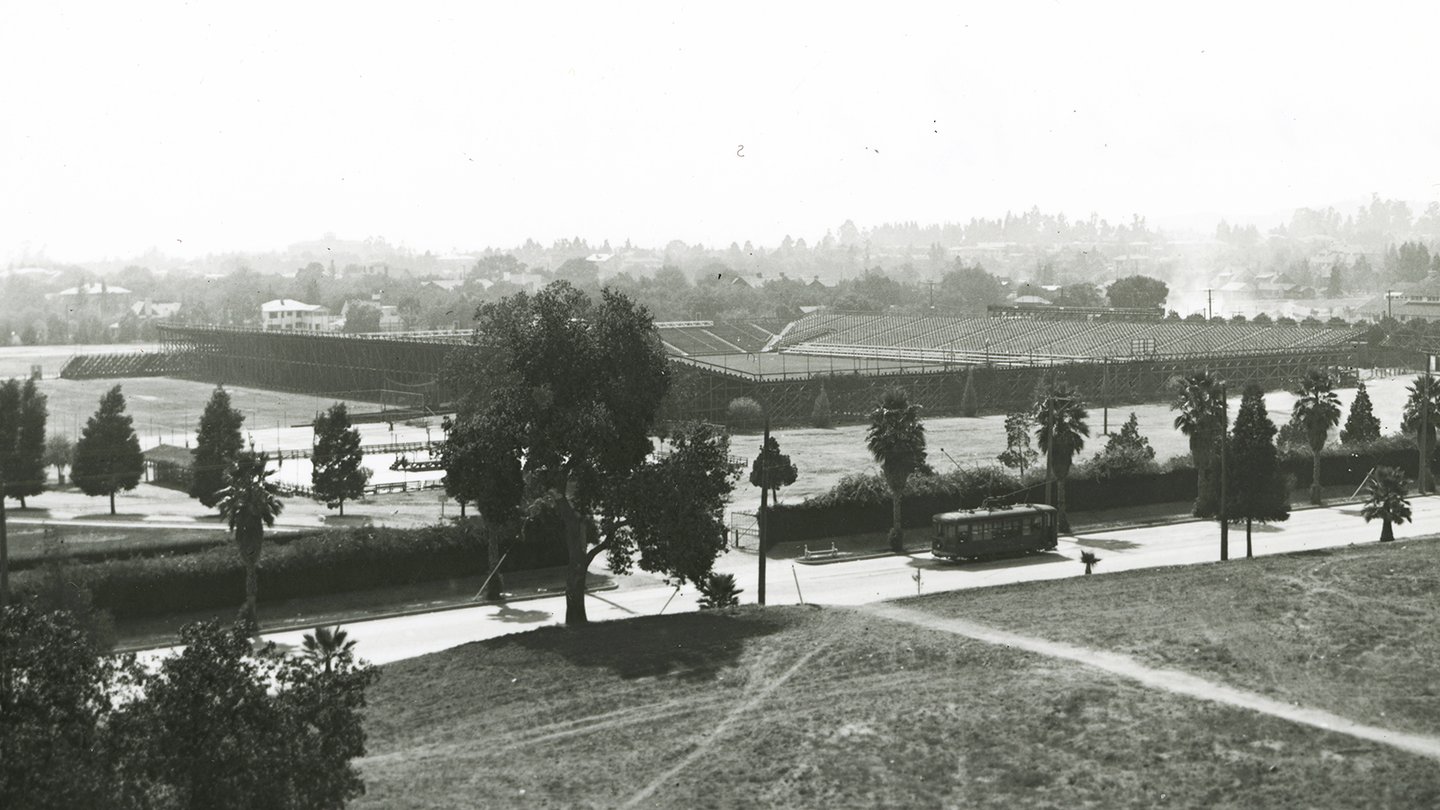 a streetcar on the road in front of an empty stadium