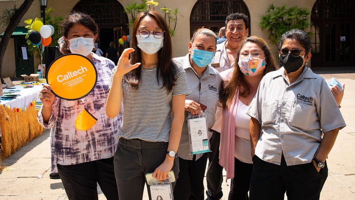 A group of people wearing masks smile at the camera