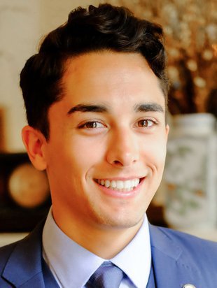 Headshot of a person with dark hair wearing a collared shirt and tie