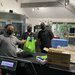 Three masked staffers prepare bags of food.