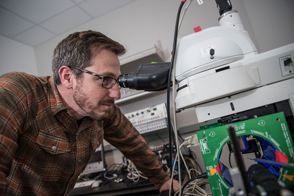 Man looking through microscope.