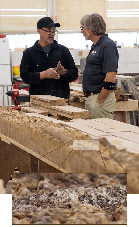 In a workshop, two men stand alongside slabs of oak