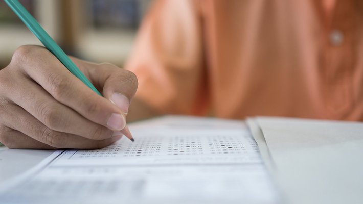 A hand holding pencil fills out a standardized test