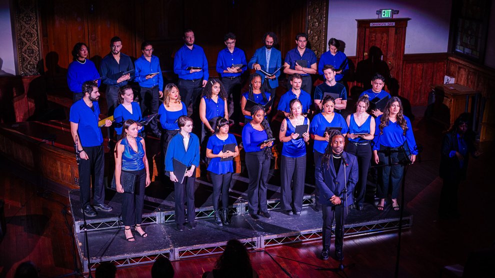 A group of singers wearing vibrant blue shirts on stage