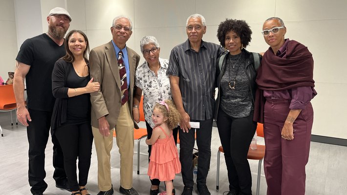 seven people and a child stand together smiling