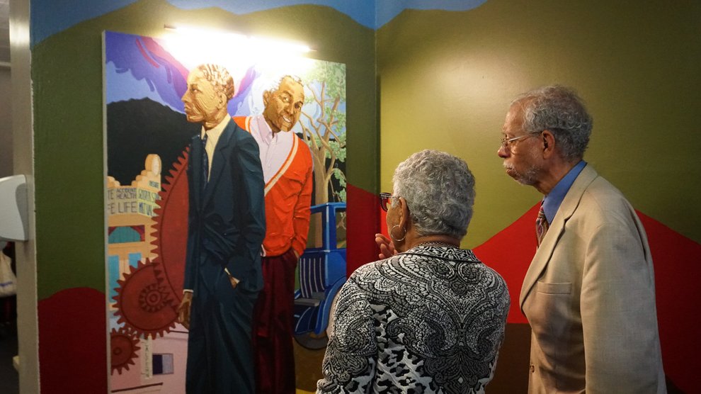 Lynda Venerable Ellington and Grant D. Venerable II look at the portrait of their father