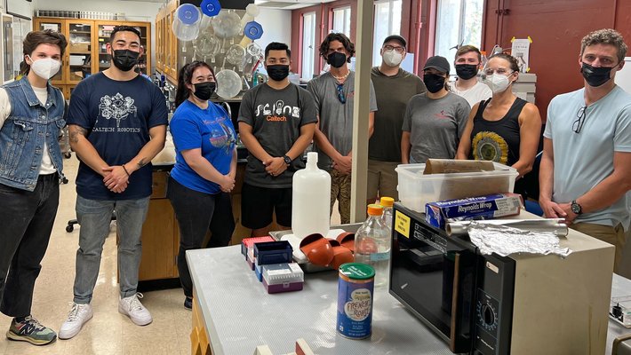 nine people wearing medical masks standing in a lab