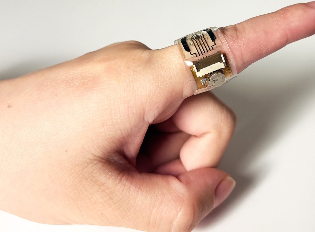 A clear film containing a sensor is wrapped around the index finger of a hand.