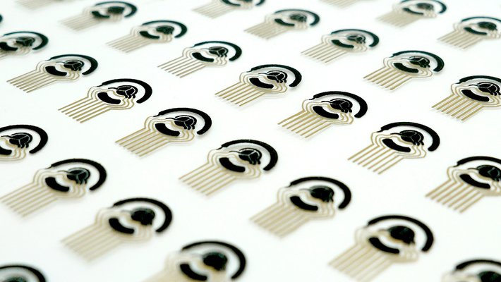 A sheet of printed out flexible sensor patch arrays. The sensors are black and gold and are on a white background.