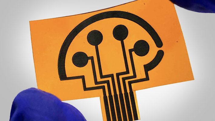 A pair of fingers clad in a blue-rubber glove hold a small orange-and-black sensor