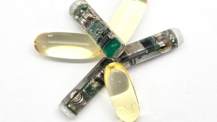 three smart capsules alternating in a flowerlike pattern with regular capsules, for size comparison purposes