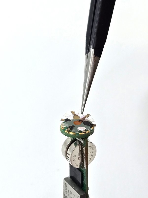 a sensor array being placed at the top of a smart capsule stack by tweezers