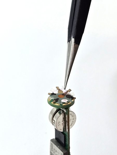 a sensor array being placed at the top of a smart capsule stack by tweezers