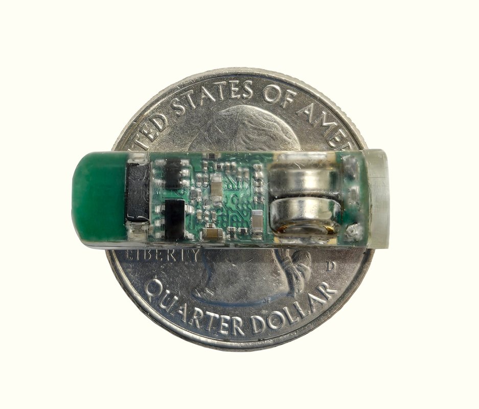 a smart capsule displayed on top of a quarter for scale