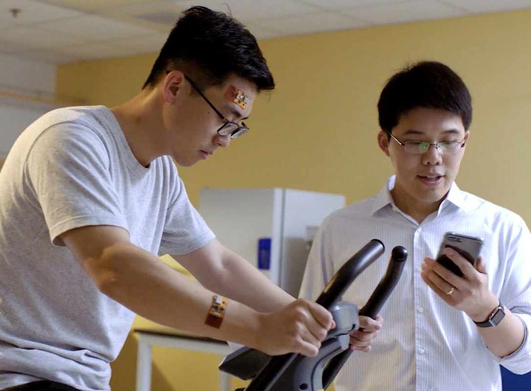 A man monitors data from flexible sweat sensors worn by a man exercising on a treadmill.