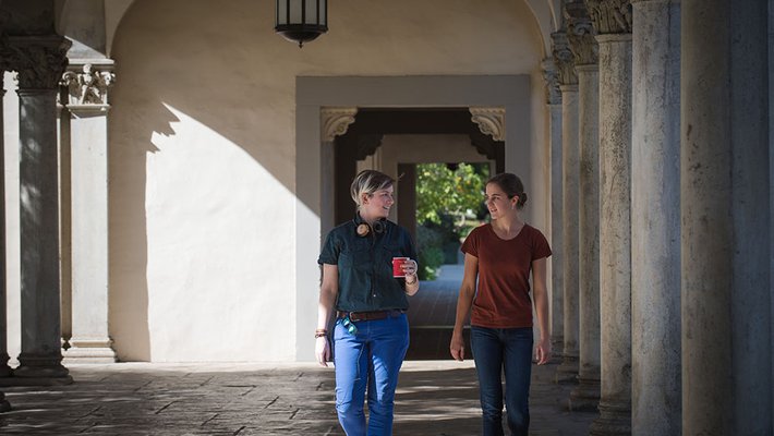Fourth-year graduate student Giuliana Viglione (left) and her mentee, first-year Cora Went (right) walk through a hallway.