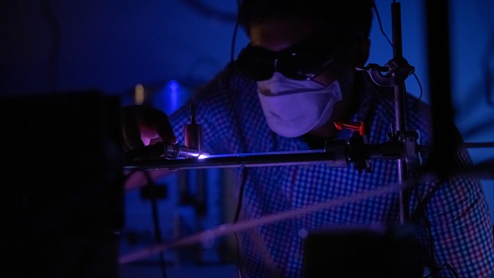 Glowing hot pink plasma can be seen in a dark laboratory room.