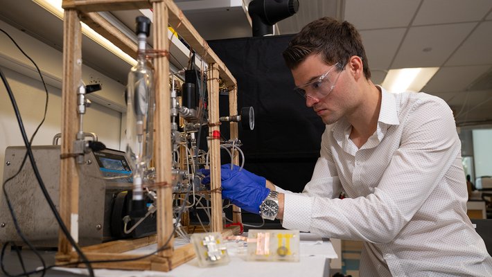 a student works with a tabletop instrument built in the lab with lots of tubing, gauges, and pumps