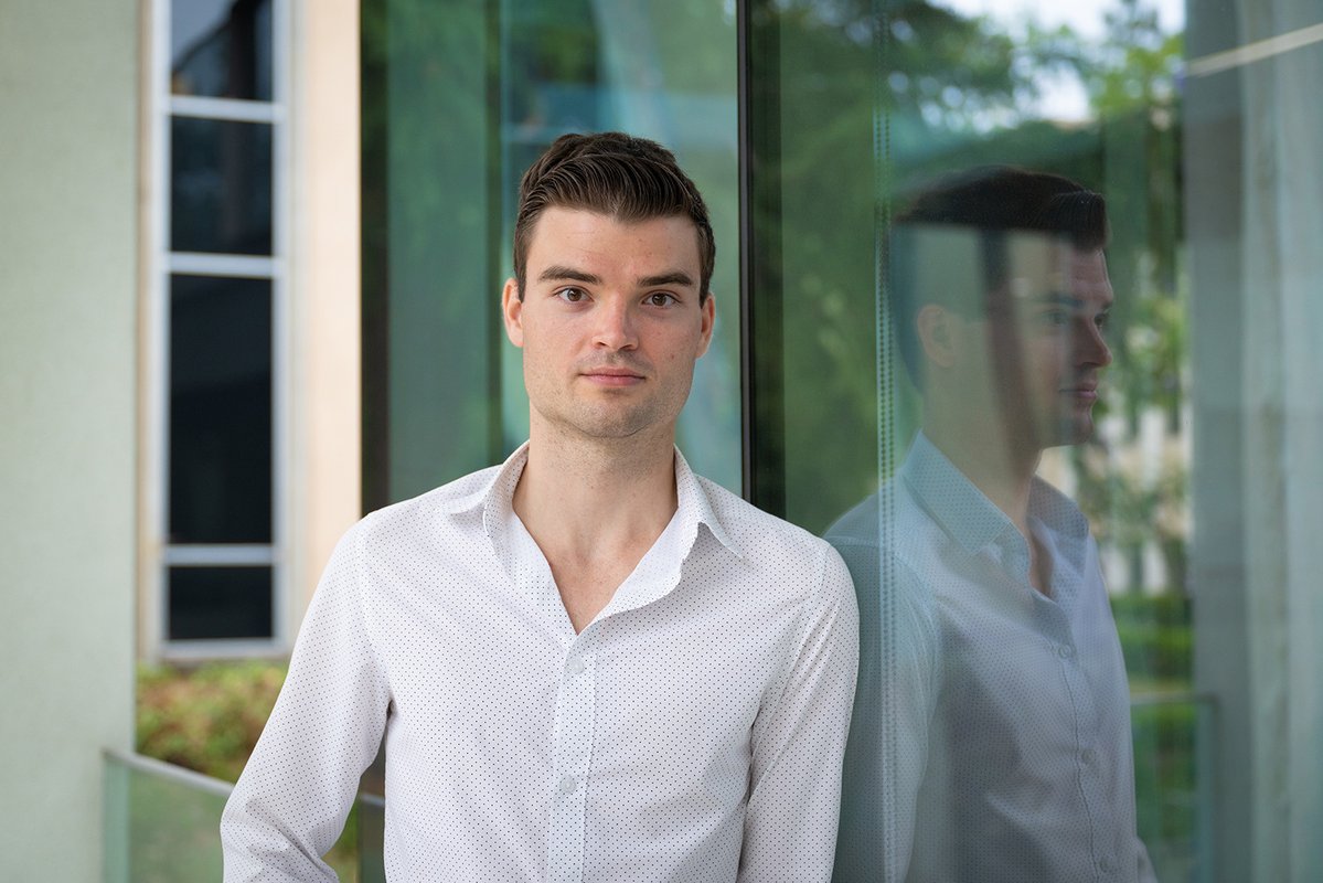 a student standing in front of a glass-sided building