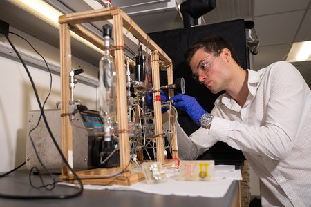 a student works with a tabletop instrument built in the lab with lots of tubing, gauges, and pumps