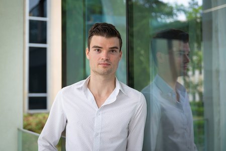 a student standing in front of a glass-sided building