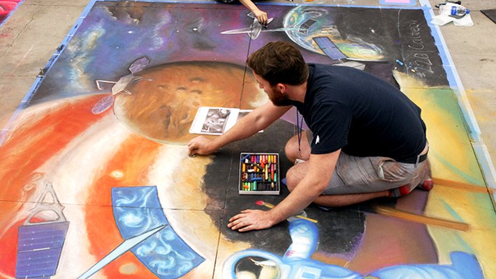 Keane (bottom) and Li apply the finishing touches to a planetary science/space exploration-themed chalk drawing at the festival on June 16.