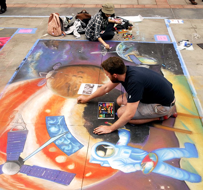 Keane (bottom) and Li apply the finishing touches to a planetary science/space exploration-themed chalk drawing at the festival on June 16.