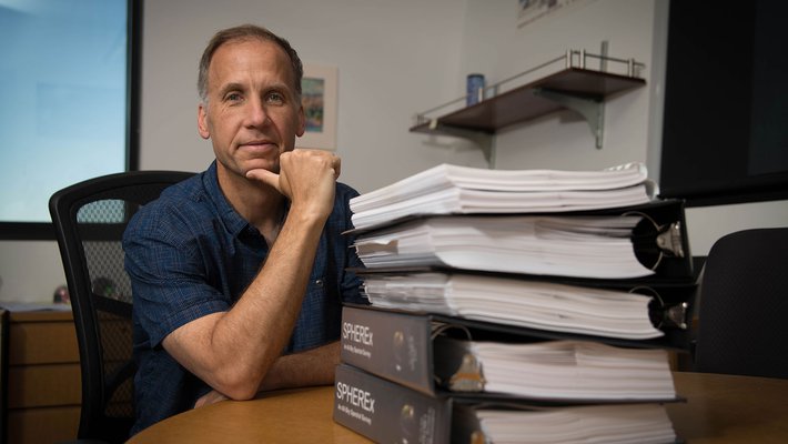 Jamie Bock and a stack of SPHEREx mission proposals.