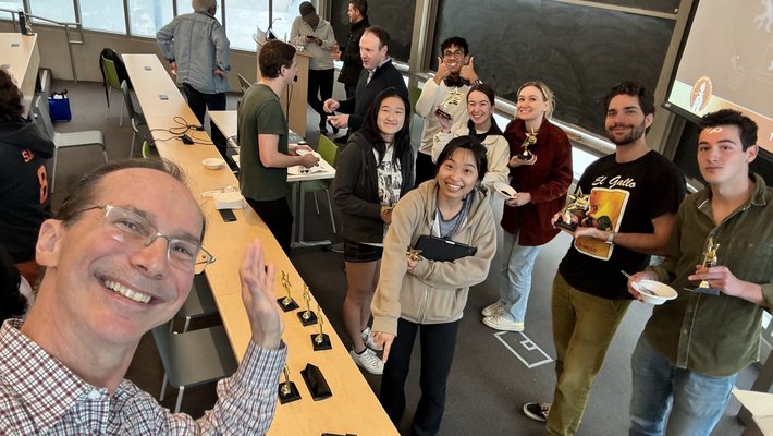 Bill Gross and Caltech students waving at the camera from their classroom.