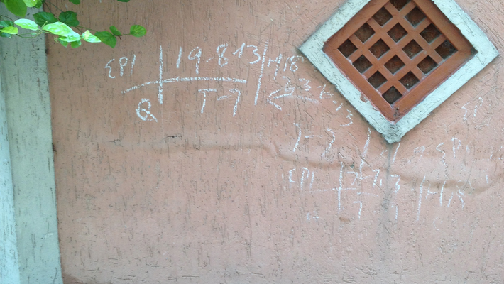 A photo of a stucco exterior wall of a house with chalk markings on it