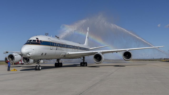 DC-8 jet plane on runway after its final flight, with a rainbow above it.