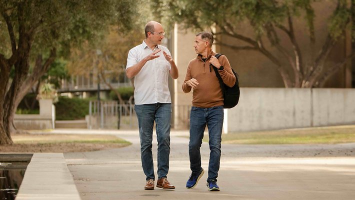 Friedrich Eberhardt and Michael Alvarez walk across Caltech's campus while conversing with one another