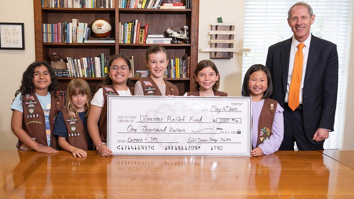 Six Girl Scout Brownies stand with Caltech President Thomas Rosenbaum holding a giant representation of the check they donated