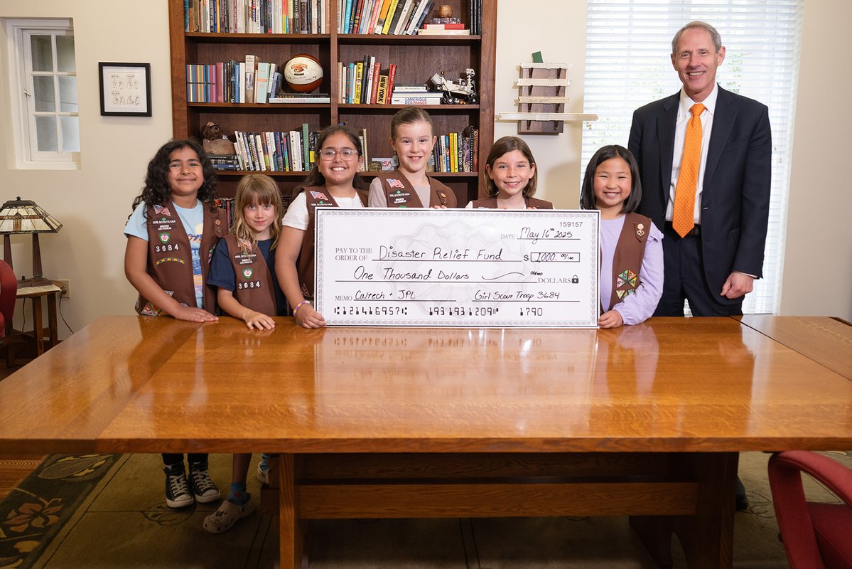 Six Girl Scout Brownies stand with Caltech President Thomas Rosenbaum holding a giant representation of the check they donated