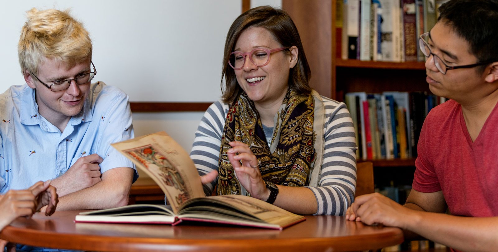 woman shows medieval manuscript to students