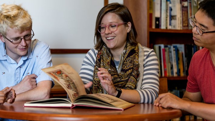 woman shows medieval manuscript to students