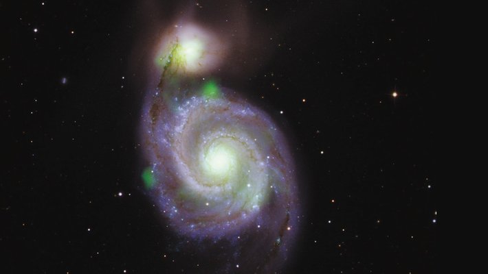 Bright green sources of high-energy X-ray light captured by NuSTAR overlaid on an optical-light image of the Whirlpool galaxy and its companion galaxy, M51b (the bright greenish-white spot above).