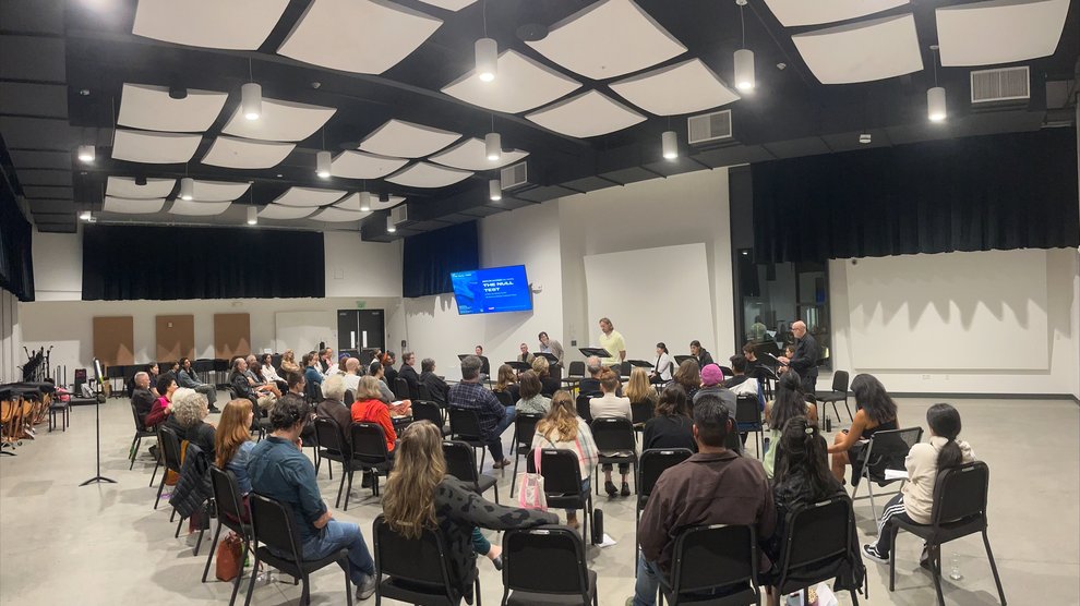 An audience of people watch a staged reading